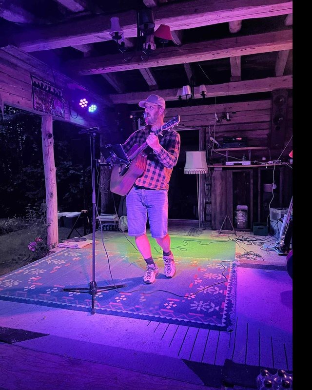 Jesper spiller guitar på en lille scene med farvet scenelys